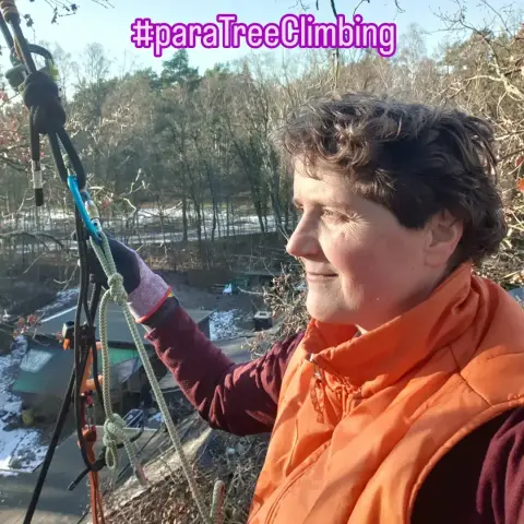 Ich bin mit Kletterausrüstung im Baum in der Sonne