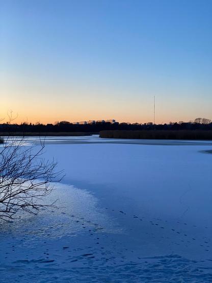Sunset photo of a snow covered frozen lake in golden hour time.
