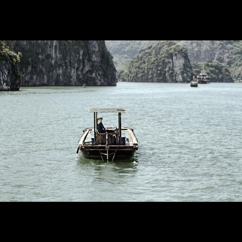 Fisherman in a little boat on the sea of Halong Bay , Vietnam