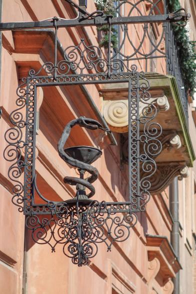 Elaborate wrought iron pharmacy sign featuring a three-dimensional serpent entwined around a goblet