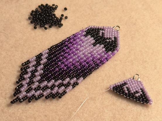An in progress pair of purple bat beaded fringe earrings on a bead mat