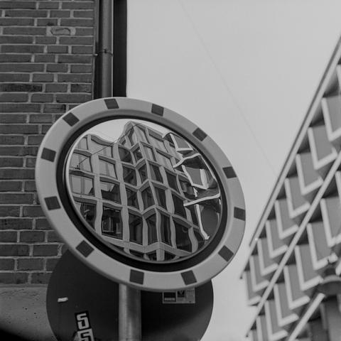 In einem Schild mit Spiegel sieht man die umstehenden Gebäude