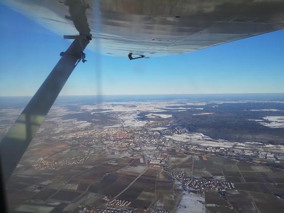Ground from inflight: towns, forests, fields. Some snow inbetween.