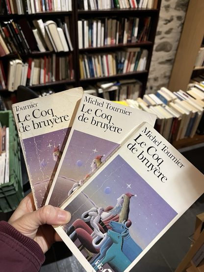 3 livres tenus dans ma main, présentés en éventail. Ils ont tous le même titre : « Le Coq de bruyère » de Michel Tournier. L’arrière plan est dans une librairie. Il y a des livres un peu partout