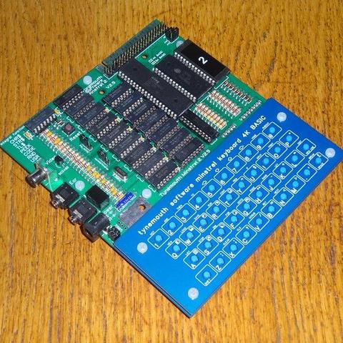 assembled Tynemouth Minstrel 2 kit. It is a green PCB with a load of black chips and a blue tactile switch keyboard.