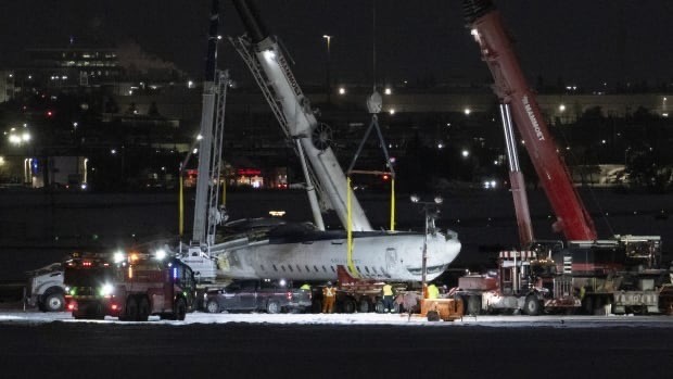 two huge white and red cranes lifting the inverted damaged Delta Air Lines jet off runway 23 at Pearson International Airport on Wednesday in the dark