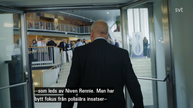 Kuvakaappaus mainitusta dokkarisarjasta. Mies kulkee selin päpin kameraan jossain julkisessa rakennuksessa. Kuvateksti: -som leds av Nivem Ronnie. Man har bytt folus från polisiära instatser -