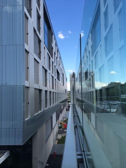 The side of a building on the left of picture reflects on a large glass barrier on the right, giving a slight impression that there are two buildings next to each other.