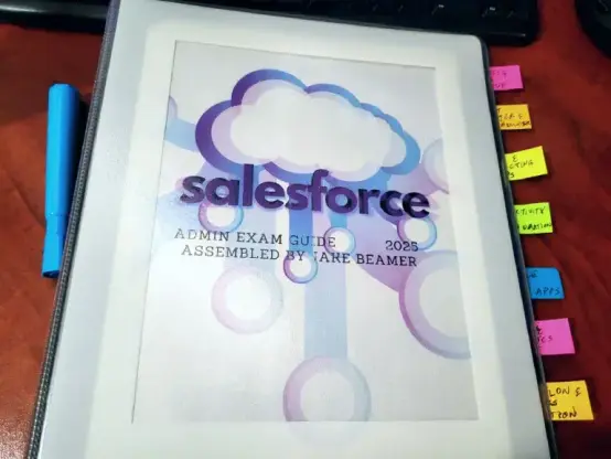 Front of the physical (printed) Salesforce admin exam study guide I made, a binder with colored tabs, blue highlighter next to it, on a wood grain desk, in front of a keyboard