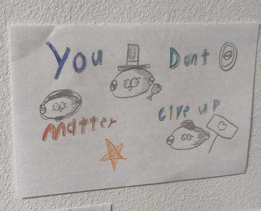 White paper with the drawings of a 4 th grader (10 years old). Top left: blue letters spell out "you."  Top middle is a pencil drawing of a seal with a top hat. Top right in turquoise letters is the word "don't." Bottom left shows orange letters spelling, "matter," with a pencil drawing of a seal with headphones above it. Bottom left shows blue letters spelling "Give up," immediately above a pencil drawing of a seal holding a sign with a heart on it.
