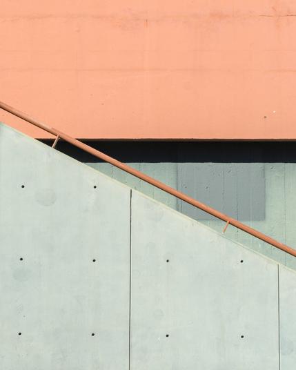 A minimalist shot of concrete stairs, with the banisters making a triangular shape against the wall behind