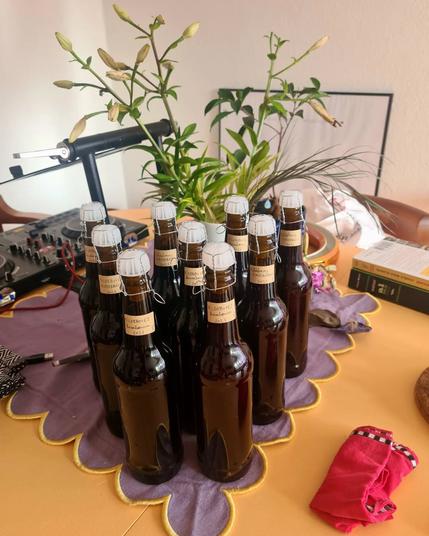 A dining table with a bunch of dark brown bottles (beer bottles). They actually contain homemade cherry wine.