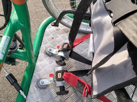 Zoom sur le système d'attache du fauteuil avec des sangles et crochets similaire à une ceinture de sécurité.