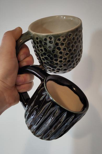 Una mà sosté dues tasses per les nanses.
