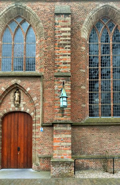 Foto van de zuidwand van de Dorpskerk in Wassenaar met de houten kerkdeur en twee glas-in-loodramen ¦ Photo of the village church of Wassenaar with the wooden church door and two windows with stained glass