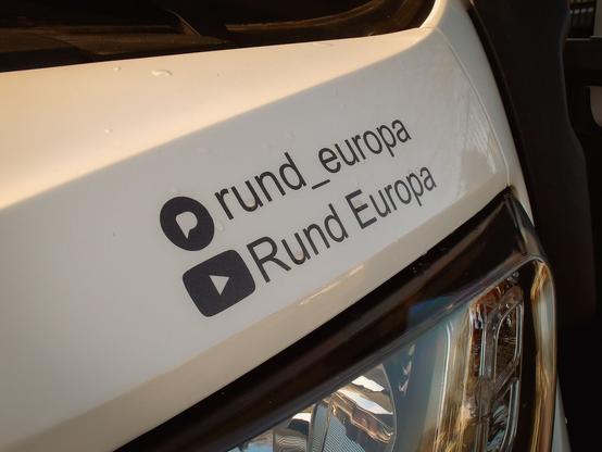 Motorhaube eines Fiat Ducatos. Darauf zwei Aufkleber. 1 - YouTube Kanal und 2- pixelfed account @rund_europa
