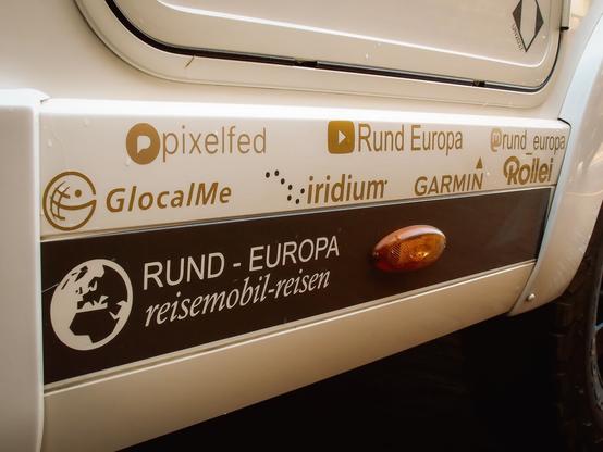 Aufkleber von Partnern an meinem Wohnmobil und der Account Name "Rund Europa" für pixelfed, YouTube und Mastodon