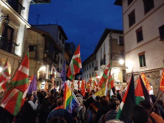 Herriko plaza jendez beteta manifestazioaren hasieran, jendea Zumardira bidean bandera eta ikurrina askorekin. Ikurrinak, LGTBI+ banderak, bandera moreak.