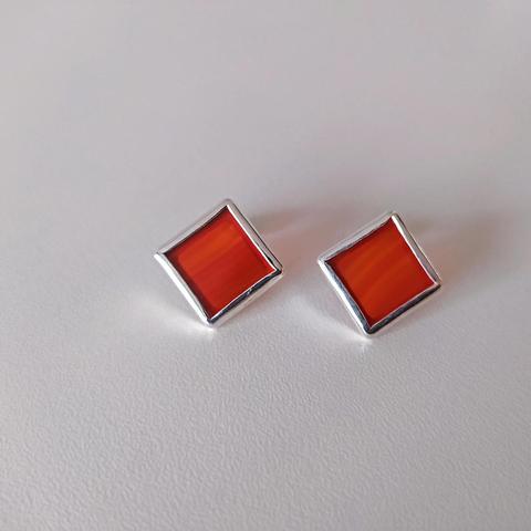 a pair of silver romboid stud earrings with red gemstone