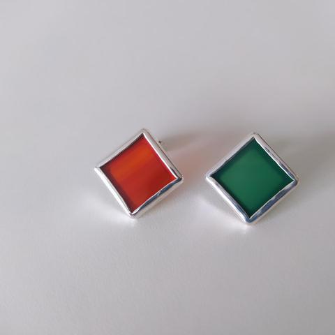 two silver romboid stud earrings one with red and one with green gemstone