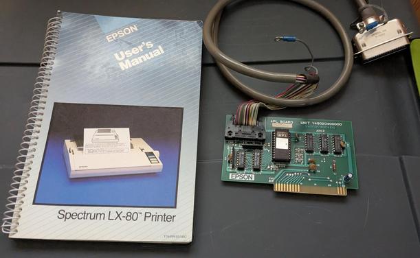 Left: spiral bound user's manual for the Epson Spectrum LX-80 printer.

Right: Expansion card attached to a centronics parallel printer cable