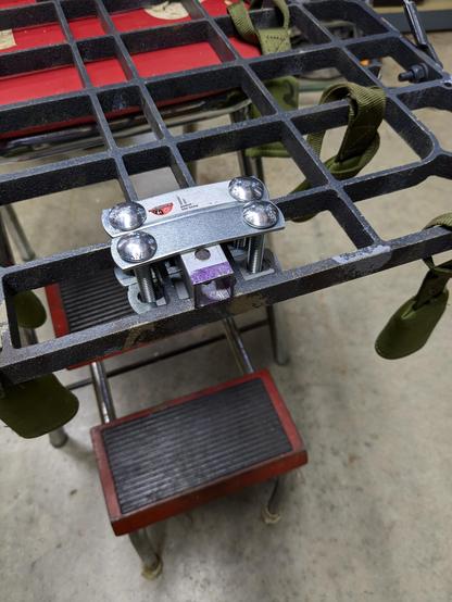 A square tube is strapped to the platform of a hunting tree stand with bolts and u-bolt mounting plates.