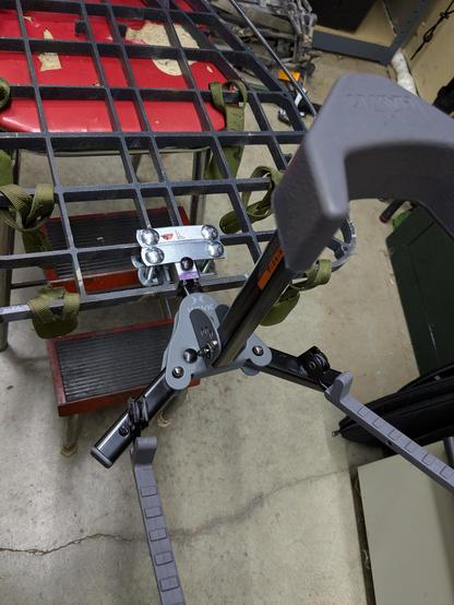 A crossbow holder is attached to a tree stand platform by a DIY fix using a square metal tube.