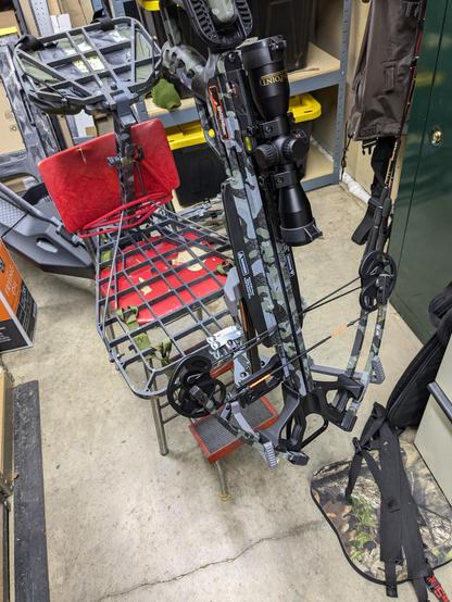 A crossbow sits in a crossbow holder that is attached to a hunting tree stand platform. This was to demonstrate that a DIY solution to make the holder attach to the platform better actually worked.