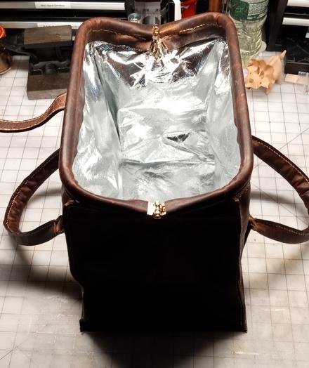 The bag fully opened to show the silver reflective interior lining designed to keep food warm or cold, depending on which is preferred. The bag is designed to be a lunch bag.