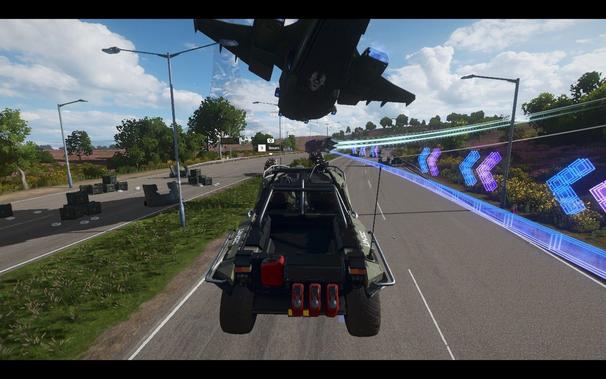The image is a digital screenshot that appears to be from a video game. It features an overhead view of an open-world environment, with a focus on the lower portion of a vehicle that seems to be a military transport truck, likely with a troop carrier or similar attachment. The truck is shown in motion on what looks like a high-speed highway or freeway, as indicated by the blurred scenery and road markings that suggest movement at high speeds.

The environment includes multiple vehicles, possibly other military trucks, moving along the same stretch of road, and there are additional smaller models of vehicles that resemble armored personnel carriers (APCs) or similar military transport vehicles in the background. The roads have a reflective surface, indicating it might be wet or there is some form of glare.

The sky is clear with no clouds visible, suggesting either early morning or late afternoon due to the soft lighting conditions. The vegetation on the sides of the road appears sparse, and there are no distinctive landmarks or features that would allow for precise geographic location identification.

In the upper part of the screenshot, there is a mini-map overlaying the scene, which includes symbols representing military bases, highways, and perhaps other relevant in-game elements. There is also text displayed on the screen, although it is partially cut off and not entirely legible due to the angle and resolution of the image.

The overall style of the image suggests a real