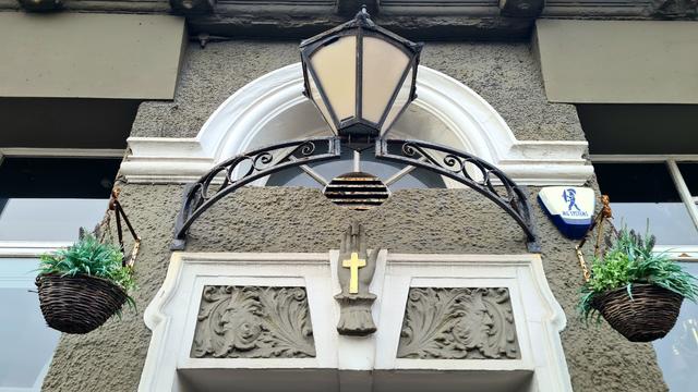 Decorative detail over the entrance to a Glasgiw bar. In the middle is an open hand with a cross on it.