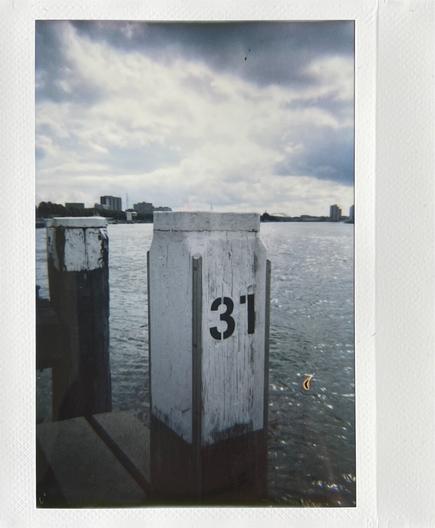 Awhite pole with the number 31 in black on it. Behind the pole is a river, and a cloudy sky.