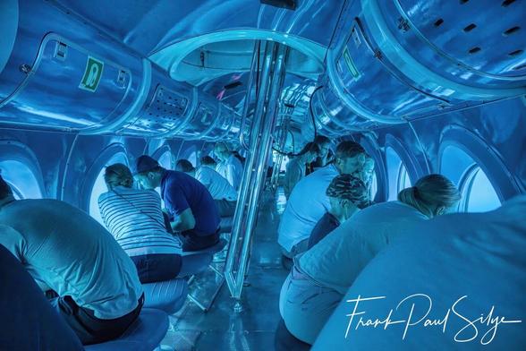 From inside a submarine - a blue light and the light from the sea make everyone look blue.
