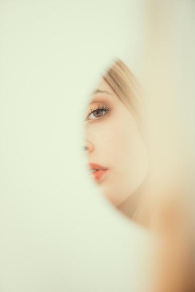 Mujer rubia reflejada en espejo redondo.
