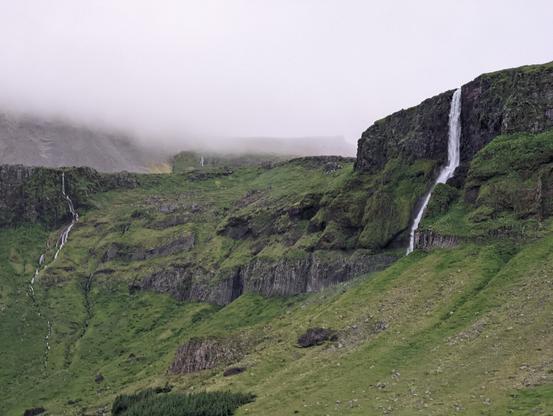 Waterfall in Iceland over green mountains