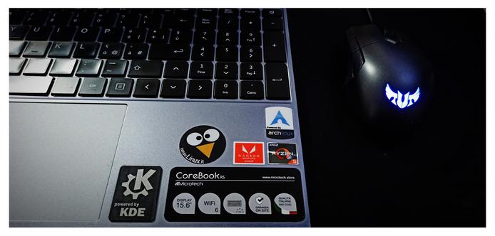 Notebook e mouse TUF, con adesivi descrittivi dell'hardware e del software