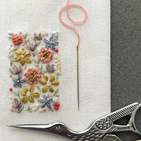 Flowers and leaves embroidered on a piece of white fabric.