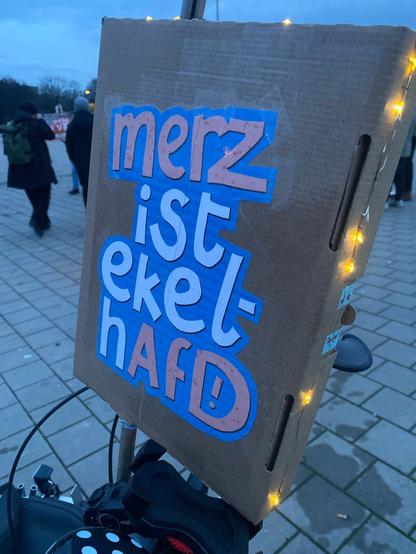Demoschild: M•rz ist ekelhAfD mit Beleuchtungslichterkette