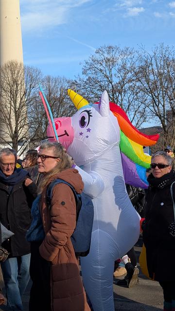 Ein Mensch in Regenbogen-Einhornkostüm protestiert gegen die Kürzungen.