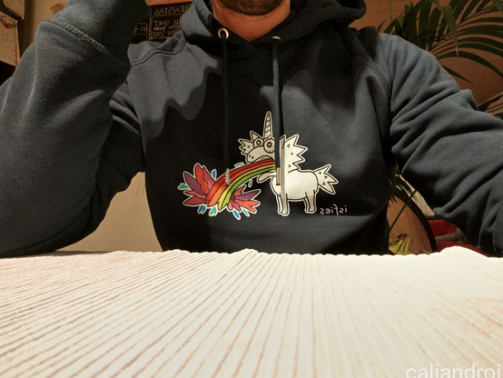 isfies Hoody mit dem Motiv eines Regenbogeneinhorns, das spucken muss und dabei seine Regenbogenfarbe ausspeit.