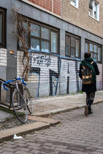 Fahrrad und Frau am Rand einer Straßenszene.