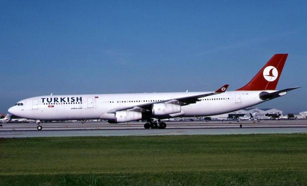Airplane is taxing by the viewer from right to left, under clear blue skies.
