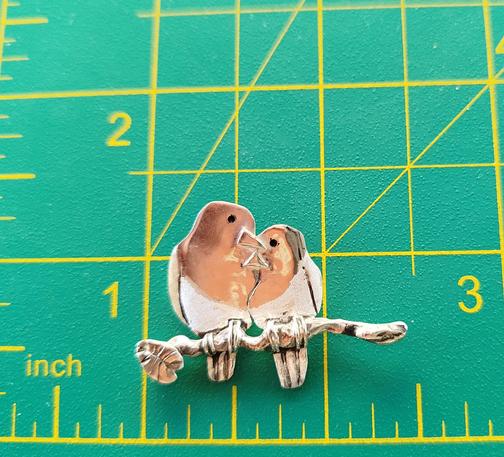 a silver pendant. it's two loving birds on a branch