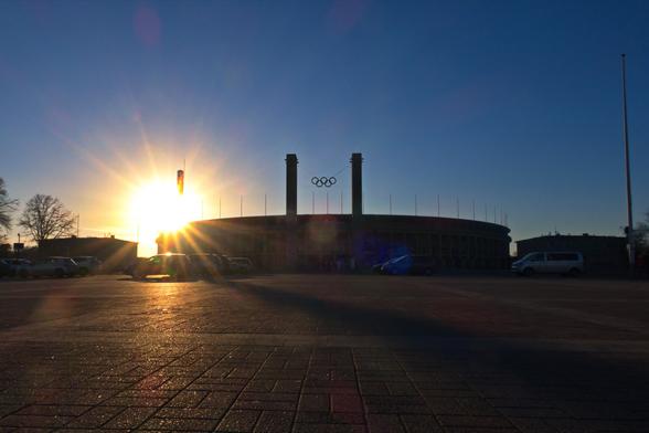 Das Berliner Olympiastadion vom Olympischen Platz aus gesehen.
An der rechten Ecke, am Glockenturm, geht die Sonne hinter dem Stadion unter.