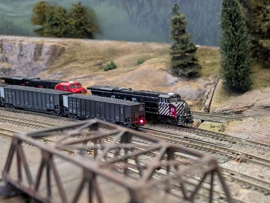A group of black Santa Fe locomotives meets the tail end of a coal drag