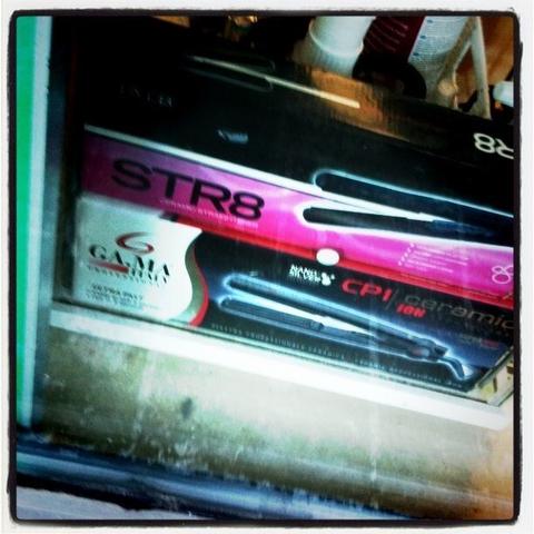 A picture of a hair straightener in its box. The label on the box reads "Str8".