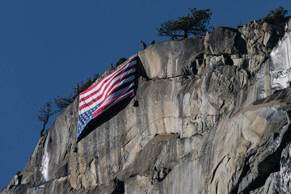 An upside-down American flag hangs from El Capitan near Yosemite National Park’s Horsetail Fall on Saturday to protest the thousands of federal job cuts made by President Donald Trump’s administration.  Tracy Barbutes/Special to the Chronicle