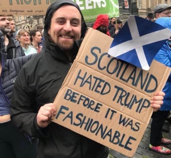 Man holding hand-written placard saying Scotland hated Trump before it was fashionable