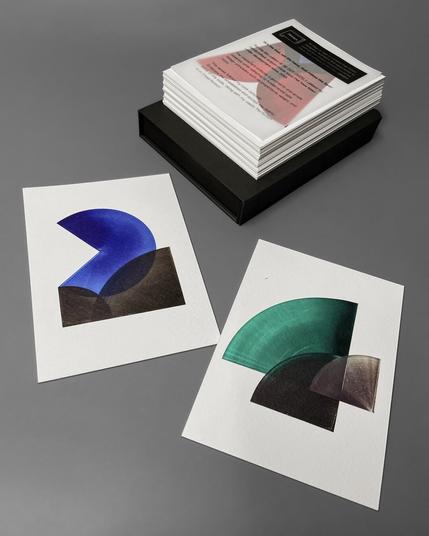 Two postcards displaying the number "24" remind us of the new year 2024. They are positioned in front of the stack of postcards in the box.