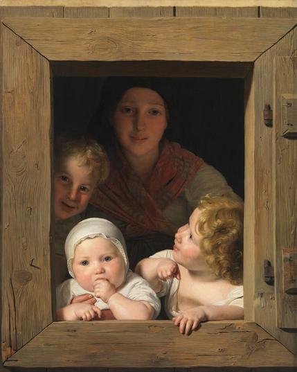 A woman and three young children are peeking through a wooden window frame. The woman, wearing a dark scarf and colorful garment, smiles gently. Two children have curly hair, while a baby with a bonnet is sucking on their thumb. The scene conveys